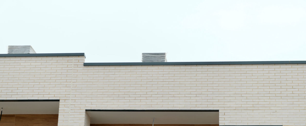 Remate de aluminio superior en fachada de ladrillo blanco