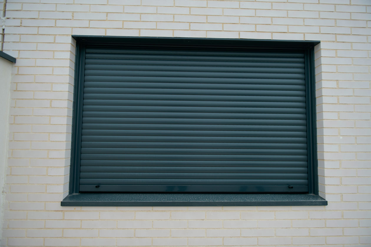 Cierre enrollable en fachada con remates de aluminio en vano